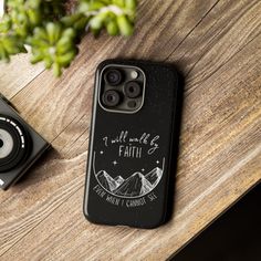 a black phone case sitting on top of a wooden table next to a small camera