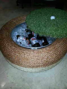 a bowl with beer bottles in it on top of some ice cubes and grass