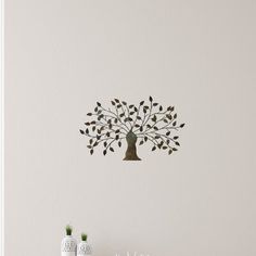 a white table topped with two vases and a tree wall hanging on the wall