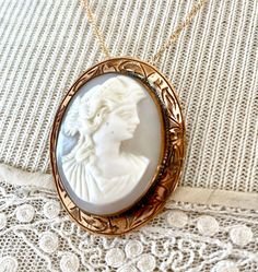 "This lovely antique, gray and white shell cameo, still a brooch, also has a \"no show\" bail that I installed. If the chain is removed, it can then be worn as a brooch. The brooch itself measures 1 1/2\" by 1 1/8\". The engraving around the rim of the bezel is beautiful. I do not know the gold content of this piece. Nor am I a cameo expert. Please check the pictures closely. The gold plated chain is 18\" long. I work with antique and vintage parts. Some may show signs of wear or age. Please loo Victorian White Cabochon Brooches, White Victorian Cabochon Brooches, White Oval Cameo Brooches, Antique Cameo Medallion Brooch, Antique Cameo Medallion Brooches, Antique White Cameo Brooch, White Oval Brooch Jewelry, White Heirloom Brooch Jewelry, Heirloom White Brooch Jewelry