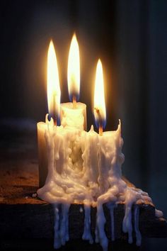 three lit candles with melting wax on them