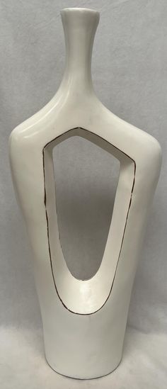 a large white vase with a hole in the middle on a plain surface, ready to be used as a sculpture