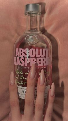 a woman's hand holding onto a bottle of absolut raspberry