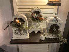 three bird houses with birds in them sitting on a shelf next to a lamp and window