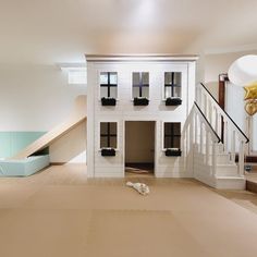 a dog is laying on the floor in front of a doll house with stairs leading up to it