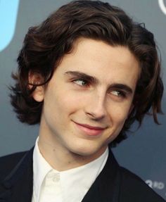 a close up of a person wearing a suit and tie with a smile on his face