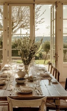 a dining room table is set with place settings for six people and has large windows that look out onto the countryside