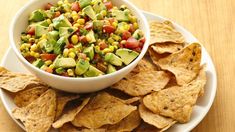 a white bowl filled with corn and avocado salsa next to tortilla chips