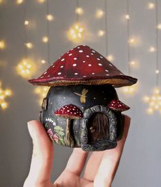 a hand holding up a small mushroom house