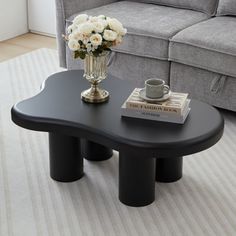 a living room with a couch, coffee table and flowers on the floor in front of it