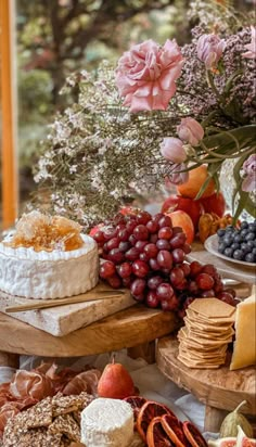 an assortment of cheeses, fruits and flowers on a table