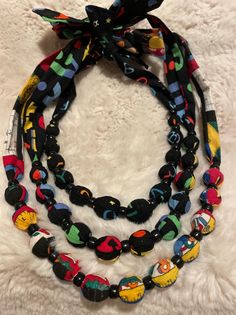 multi - colored beaded necklaces on white furnishing, with black ribbon