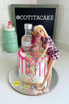 a barbie doll cake with sprinkles on it and a bottle of vodka