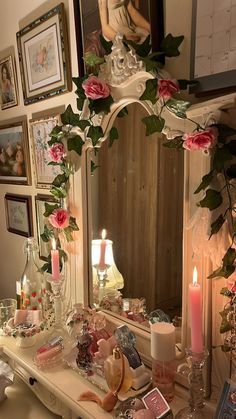 a vanity with candles and pictures on the wall above it is decorated with roses, leaves and other things