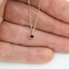 Very classy, simple, and dainty. This handcrafted gold pendant has a natural Garnet stone and comes on your choice of a 16 or an 18 inch gold chain with the artist's tag attached to the clasp. It can also be paired with other pendants! Mix and match to create your own personalized necklace or mother necklace! Gold is 14ky. Stone measures 3mm in diameter. Birthstone for January. All Laine Benthall jewelry comes with a lifetime warranty. This pendant can also be purchased without the chain, just g Minimalist Recycled Gold Necklace With Birthstone, Minimalist Birthstone Necklace In Recycled Gold, Minimalist Recycled Gold Birthstone Necklace, Dainty 14k Gold Birthstone Necklace With Round Pendant, Recycled Gold Gemstone Birthstone Necklace As A Gift, Recycled Gold Birthstone Gemstone Necklace For Gift, Recycled Gold Birthstone Necklace As Gift, Minimalist 14k Gold Charm Necklaces With Gemstone, Minimalist 14k Gold Gemstone Charm Necklace