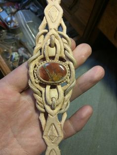 a hand holding a piece of leather with a stone embedded in it's center