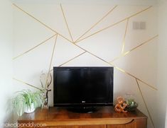 a flat screen tv sitting on top of a wooden dresser next to a potted plant