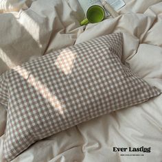 a brown and white checkered pillow sitting on top of a bed next to a book