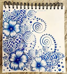 a spiral notebook with blue flowers and swirls on it