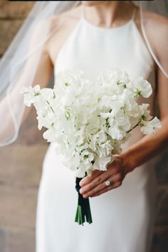 a bride holding a bouquet of white flowers