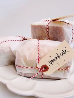 two soap bars wrapped in white paper on a plate with red twine and tag