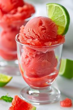 two glasses filled with watermelon ice cream and lime wedges on the side