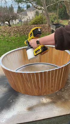 a person using a power drill to paint a wooden bowl with wood slats on it