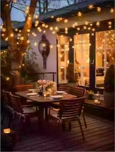 an outdoor dining area is lit up with fairy lights