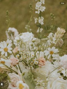 a vase filled with white and pink flowers on top of a grass covered field,