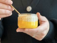 a person holding a jar with honey in it and a wooden stick sticking out of it