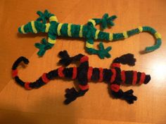 two toy lizards sitting on top of a wooden table