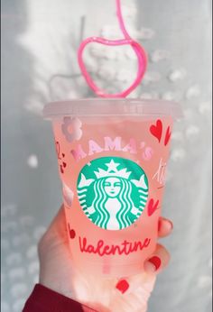 a person holding up a pink starbucks cup