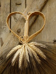 a heart shaped piece of straw tied to a wooden door with a rope around it