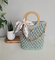 a handbag sitting on top of a white table next to a potted plant