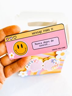 a person holding up a pink card with a smiley face on it and the words mensue para it