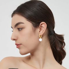 This pair of earrings features a lustrous solitaire shell pearl and a radiant gold hoop, creating a harmonious balance of classic and modern. The delicate huggie hoop is adorned with brilliant pavé set zirconia, adding a touch of sparkle and glamour that beautifully complements the pearls. These earrings effortlessly transition from day to night, from casual to formal events. Whether you're attending a wedding, a dinner party, or simply adding a touch of luxury to your everyday attire, these ear Modern White Earrings With Pearl Charm, Modern White Pearl Earrings For Everyday, Modern White Round Pearl Earrings, Modern Pearl White Earrings With Pearl Charm, Modern White Pearl Hoop Earrings, Modern White Single Pearl Earring, Modern Gold Hoop Earrings With Pearl Charm, Trendy White Hoop Pearl Earrings, Modern Hoop Earrings With Pearl Charm