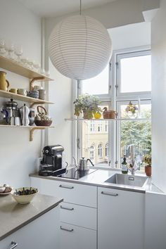 a kitchen filled with lots of counter top space next to a large open window covered in white curtains