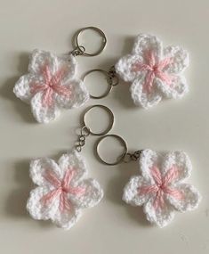 four crocheted keychains with pink and white flowers