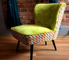 a green chair sitting on top of a hard wood floor next to a brick wall