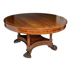 an oval wooden table with carved legs and a center piece on one end, in the shape of a lion's paw