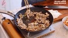 a wok filled with food sitting on top of a stove next to a bowl