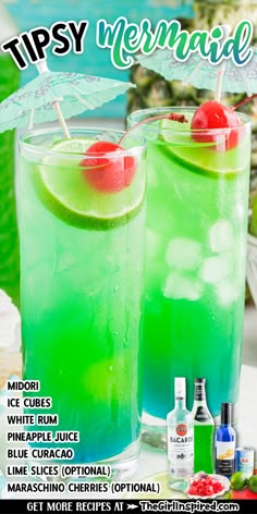 two glasses filled with green liquid and topped with cherries on the rim are sitting next to each other