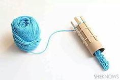 a blue ball of yarn next to a crochet hook on a white surface