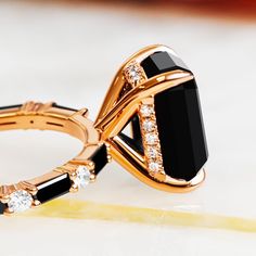 a gold ring with black onyxite and white diamonds in the middle, sitting on top of a table