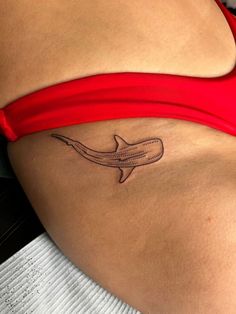 a woman's stomach with a tattoo of a shark on the lower part of her belly