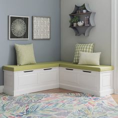 a corner bench with two pillows on it in a living room next to a rug