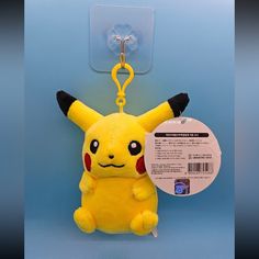 a yellow stuffed pikachu keychain hanging from a hook on a blue background