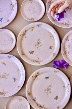 a table topped with lots of white plates covered in purple and yellow butterflies on them