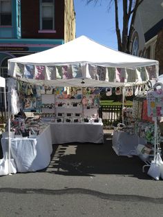 an outdoor market with white tents and cloths on display in front of the building