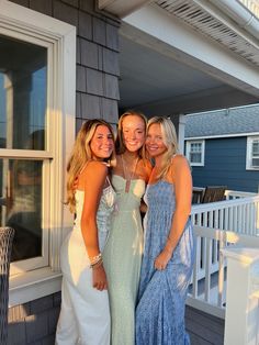 three beautiful women standing next to each other in front of a house on the porch